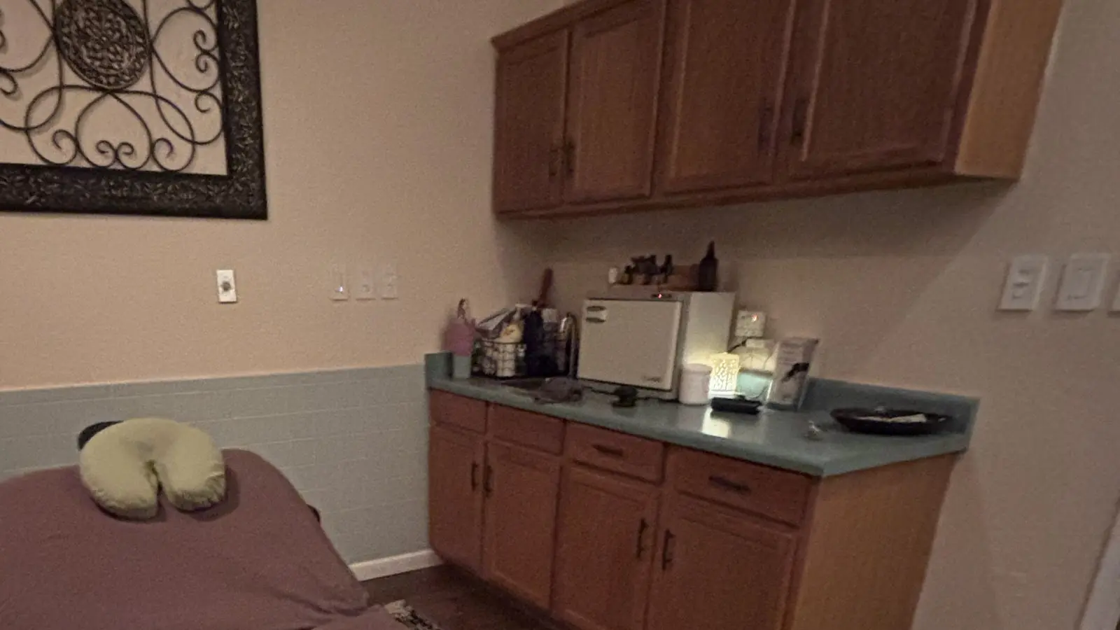 The treatment room counter with a warm lamp, towel warmer and oils, and the head of the table below